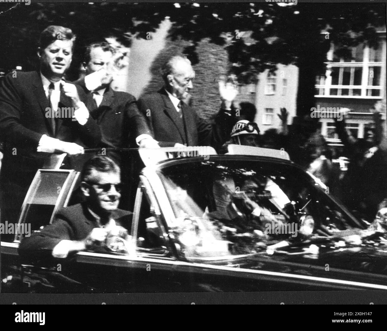 John Fitzgerald Kennedy (links), Willy Brandt (Mitte) und Konrad Hermann Joseph Adenauer (rechts) in Kennedys Auto während der Fahrt durch Berlin. Stockfoto