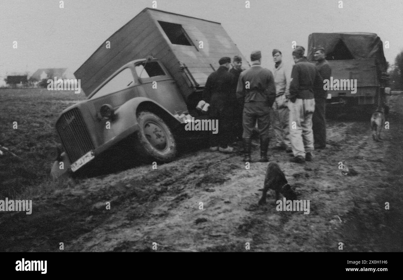 Ein Militärwagen war in einen Graben gerutscht. In der Mitte des Bildes diskutieren die Soldaten über die Situation. Stockfoto