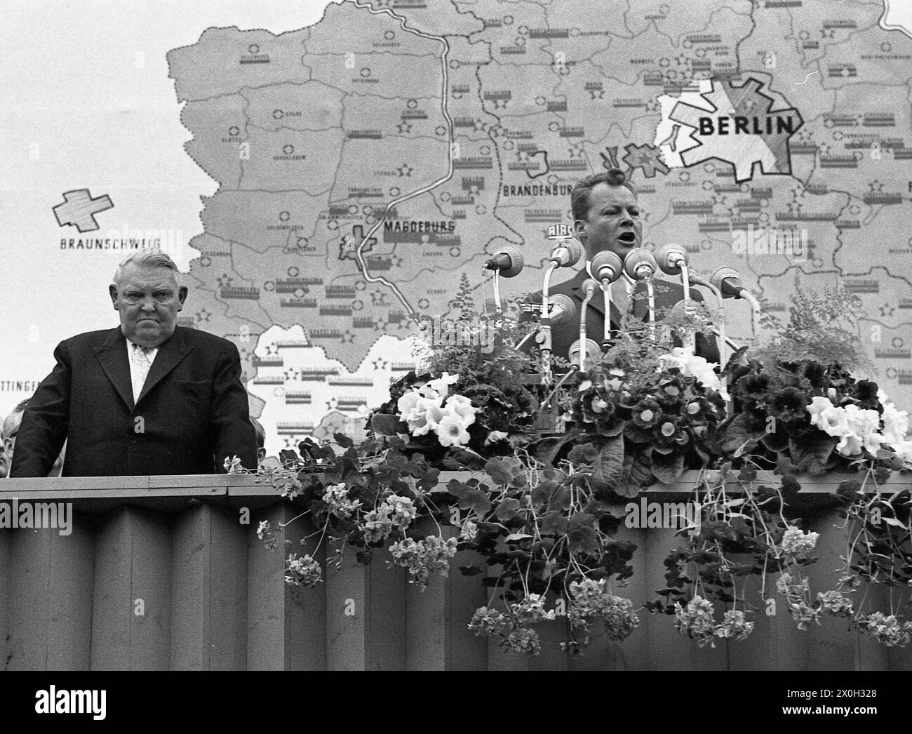 Der regierende Bürgermeister von Berlin Willy Brandt mit Ludwig Erhard während einer Rede zum ersten Jahrestag des Baus der Berliner Mauer vor dem Schöneberger Rathaus in Berlin. Stockfoto