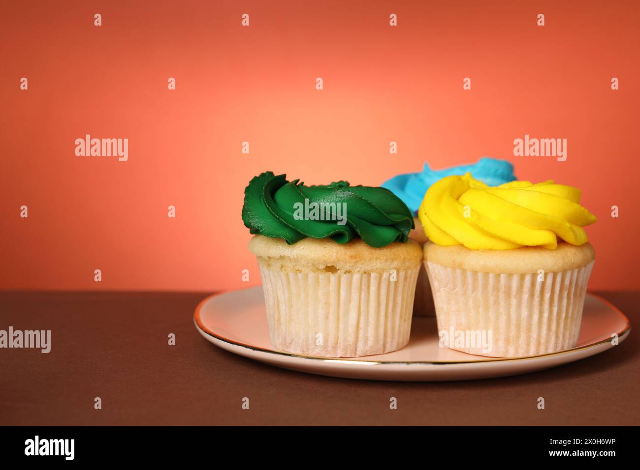 Köstliche Cupcakes mit heller Creme auf farbigem Hintergrund, Platz für Text Stockfoto