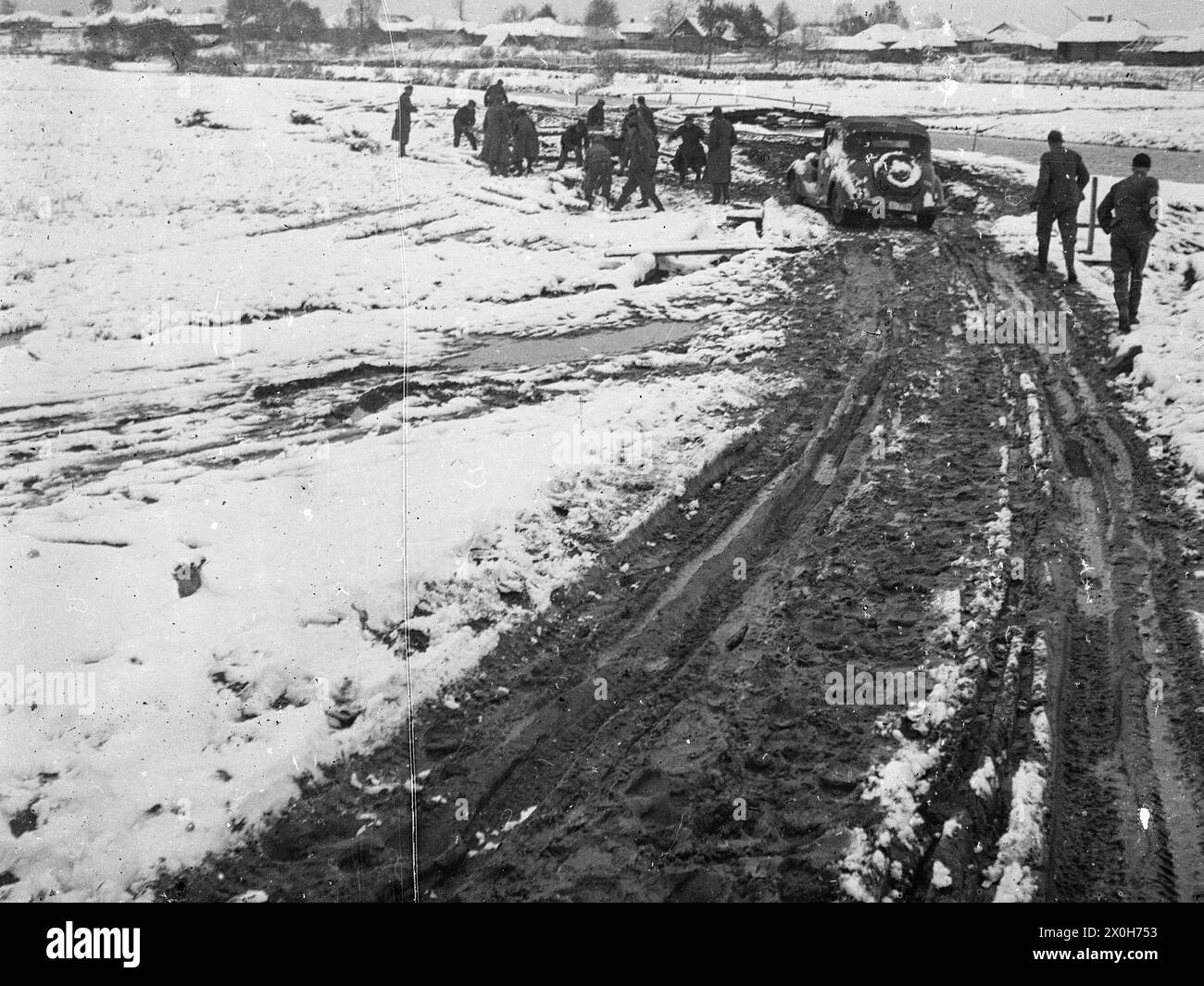 Auf der russischen Festivalroute steckt ein führendes Auto im Schlamm fest. Soldaten versuchen, die Straße mit Baumstämmen befahrbar zu machen. Das Bild wurde von einem Mitglied des Radfahrgrenadierregiments 2/Radfahrsicherungsregiment 2 im Nordteil der Ostfront aufgenommen. [Automatisierte Übersetzung] Stockfoto