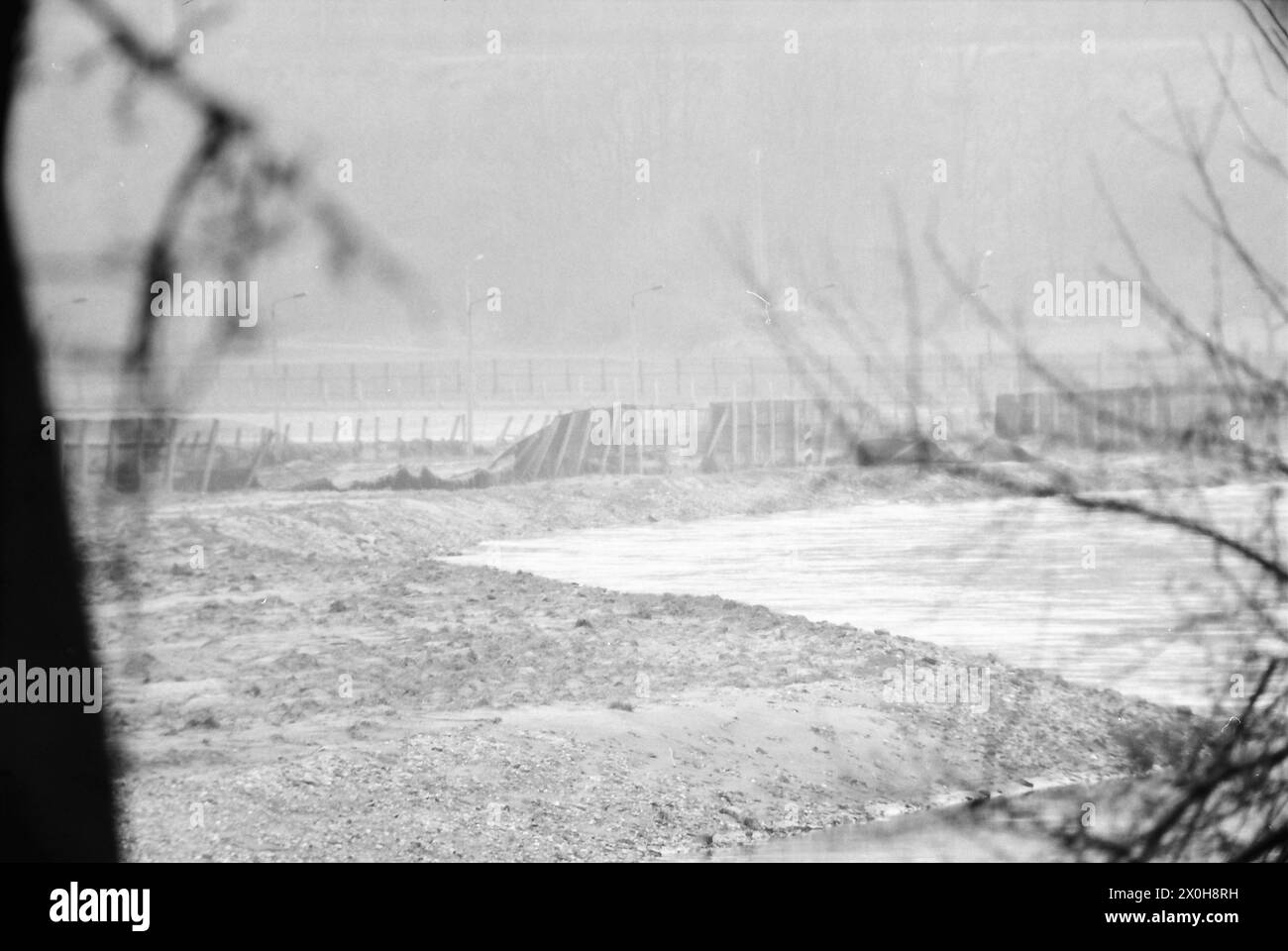 Eine Teleaufnahme entlang der Werra zeigt den erweiterten Metallzaun hier als ersten und dritten Zaun, der am Flussufer offenbar abgerissen wurde. Die Lichtmasten sind noch immer im Dunst der Aufnahme zu sehen [automatisierte Übersetzung] Stockfoto