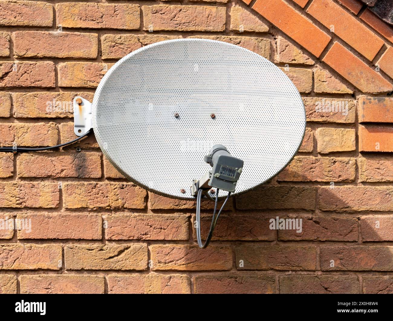 Der alte, verwitterte digitale Satellitenempfangsgerät-Mehrkanaldecoder ist an einer Ziegelwand befestigt Stockfoto