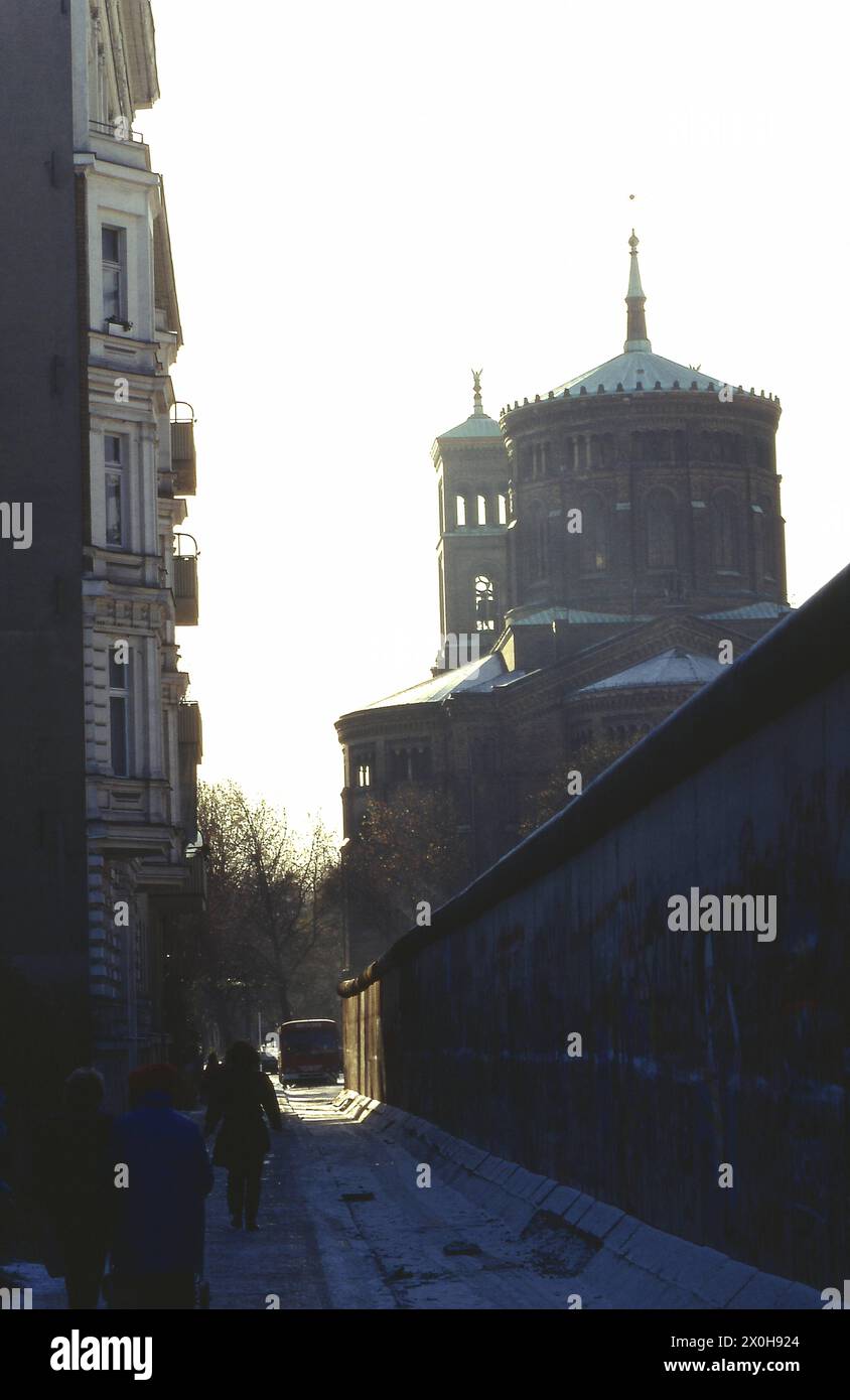 Berlin Kreuzberg, die Mauer steht so nahe am West-Berliner Wohnhaus, dass nicht einmal ein Bus durchkommt. St. Thomas Church auf der rechten Seite. [Automatisierte Übersetzung] Stockfoto