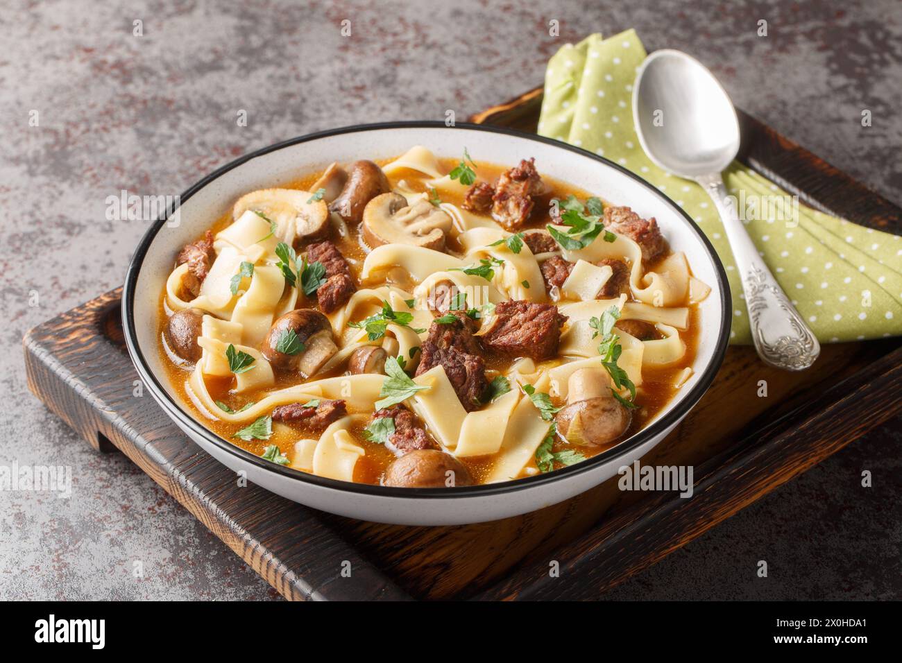 Stroganoff-Suppe wird mit Rindfleisch, Pilzen und Nudeln in einer duftenden cremigen Brühe in einer Schüssel auf dem Tisch zubereitet. Horizontal Stockfoto