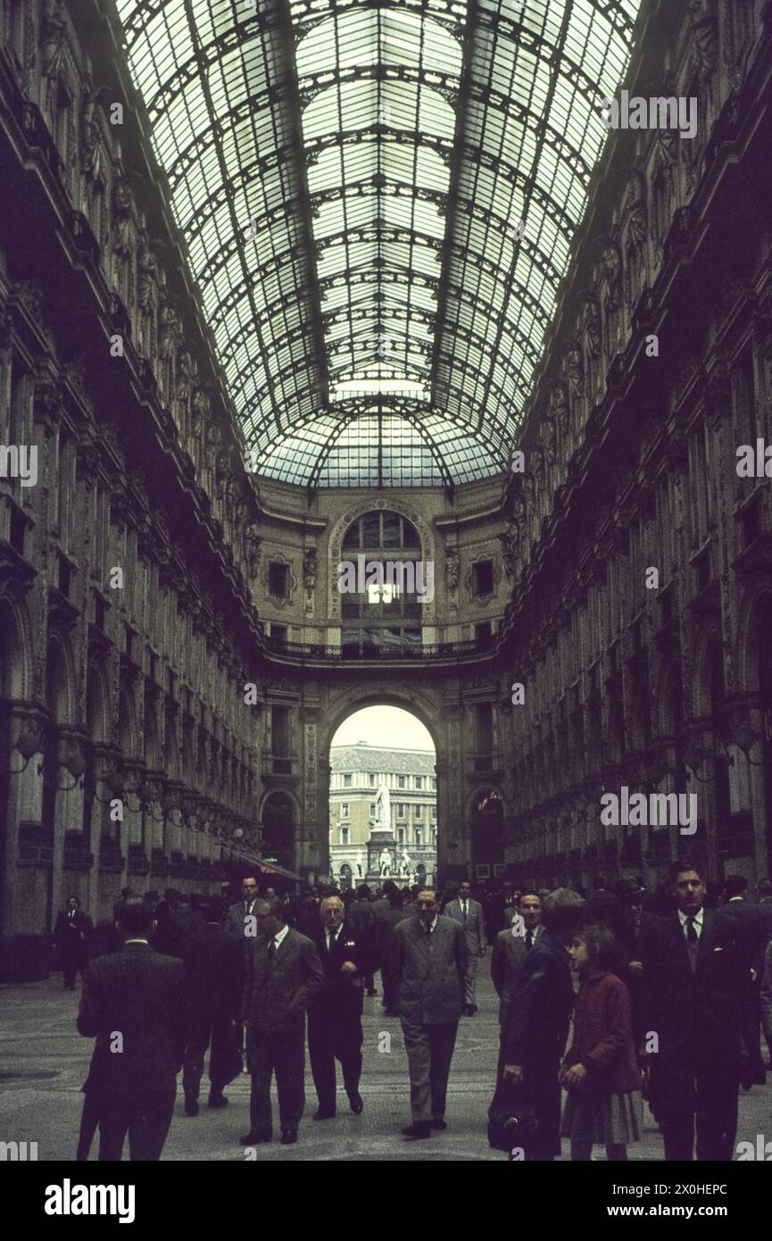 Blick auf Passanten und das Glasdach von der Einkaufsmeile. Am Ende der Galerie ist die Statue von Leonardo da Vinci auf der Piazza della Scala zu sehen. [Automatisierte Übersetzung] Stockfoto