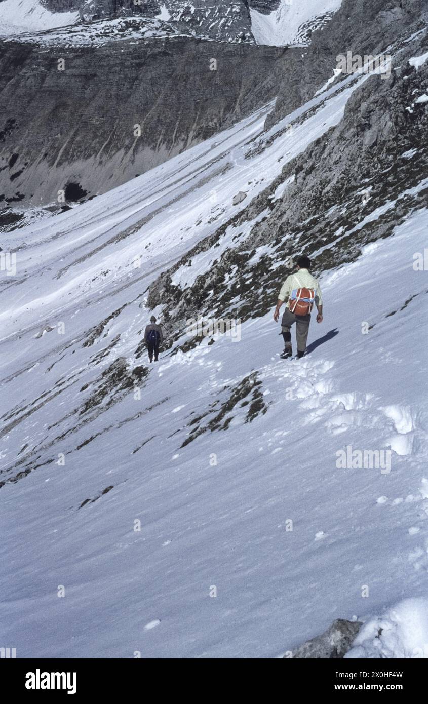 Zwei Wanderer steigen von der Mandlscharte auf dem schneebedeckten Weg ab. [Automatisierte Übersetzung] Stockfoto