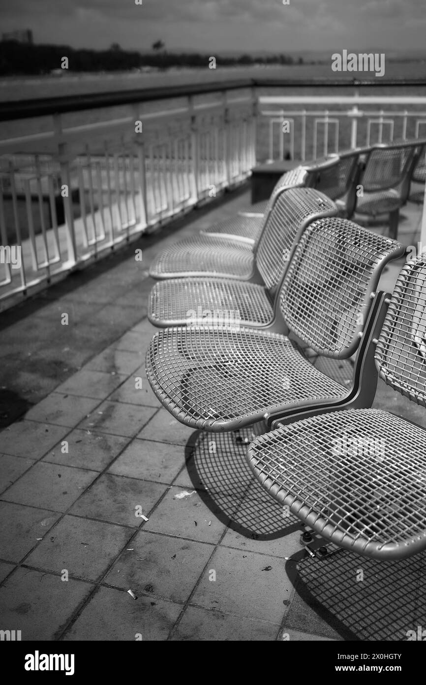 Reihe von Metallstühlen auf dem Pier Stockfoto