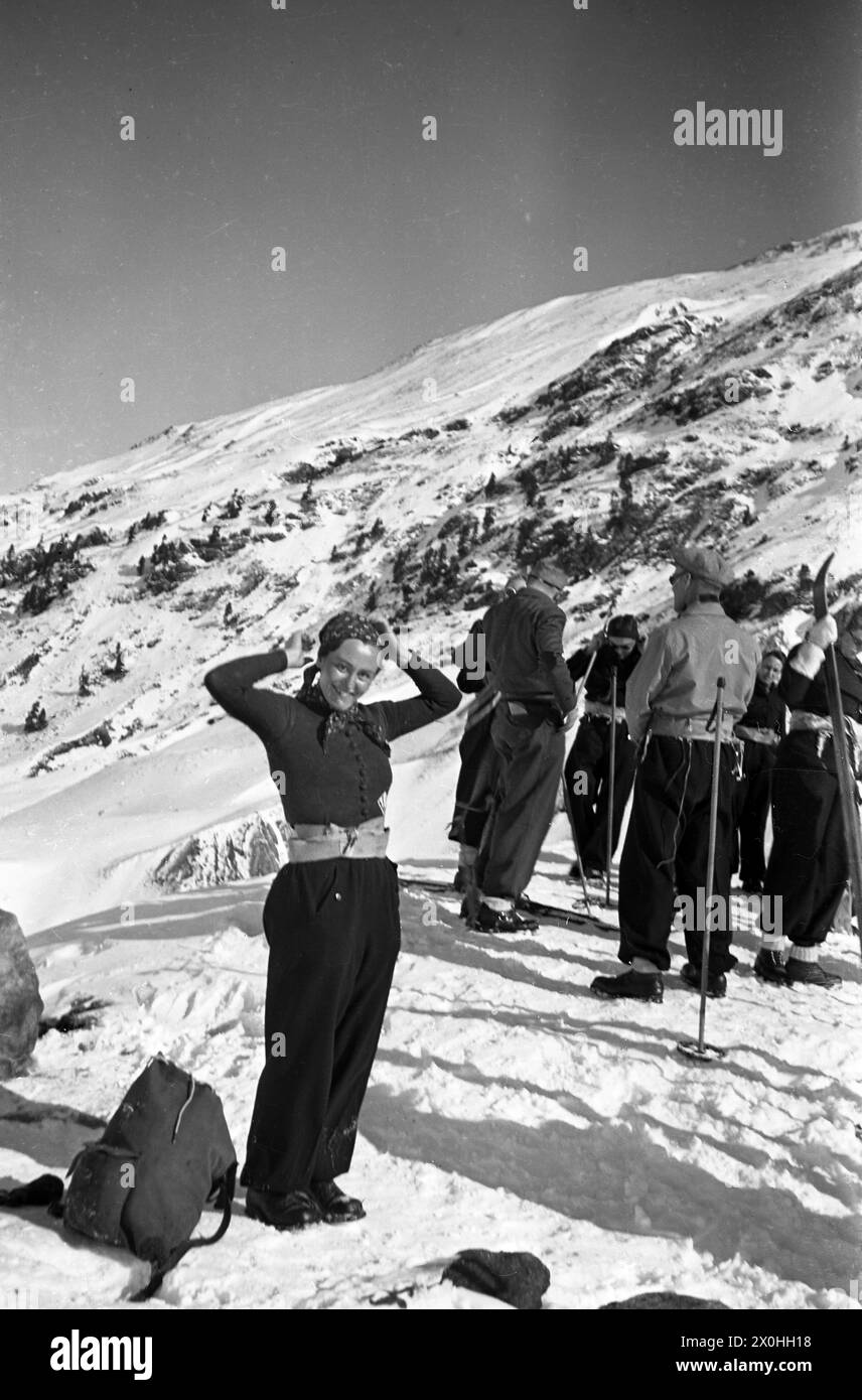 Eine junge Frau posiert für ein Foto vor einer Gruppe von Skifahrern in den Schweizer Alpen. [Automatisierte Übersetzung] Stockfoto