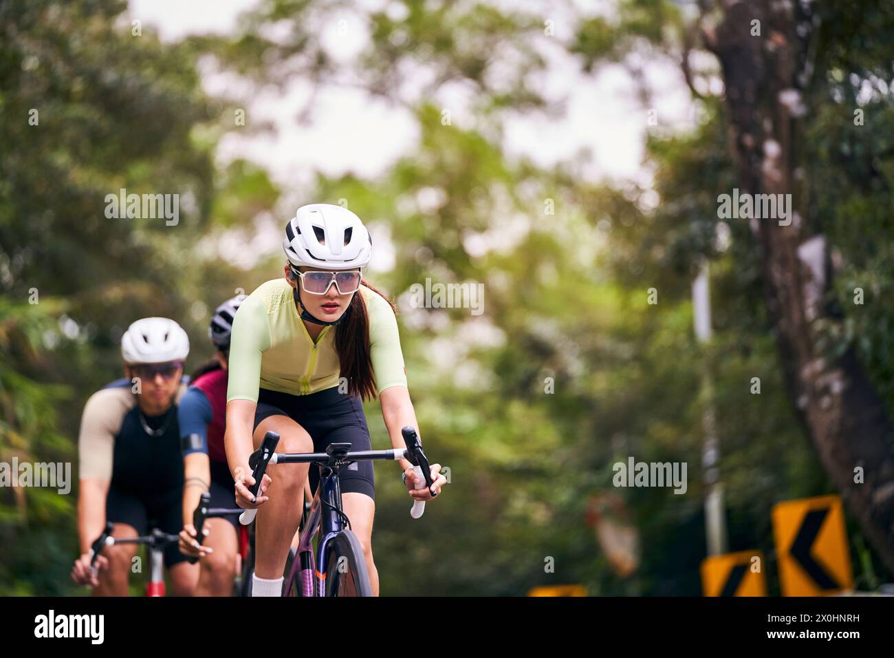 Gruppe von drei jungen asiatischen erwachsenen Radfahrern, die Fahrrad auf der Landstraße fahren Stockfoto