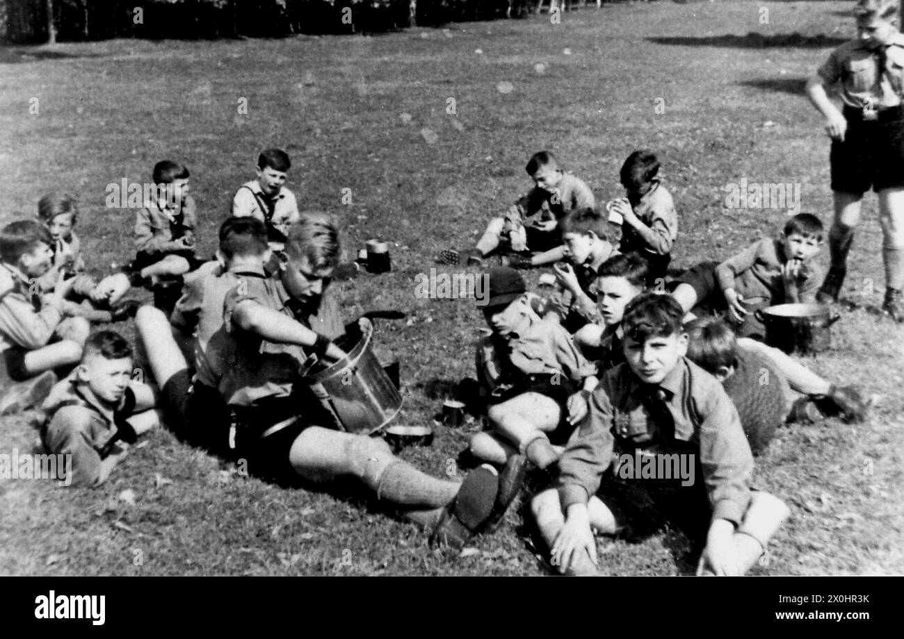 Junge Mitglieder der Hitlerjugend bei einer Mahlzeit auf einer Wiese in Ochsenfurt im Mai. [Automatisierte Übersetzung] Stockfoto