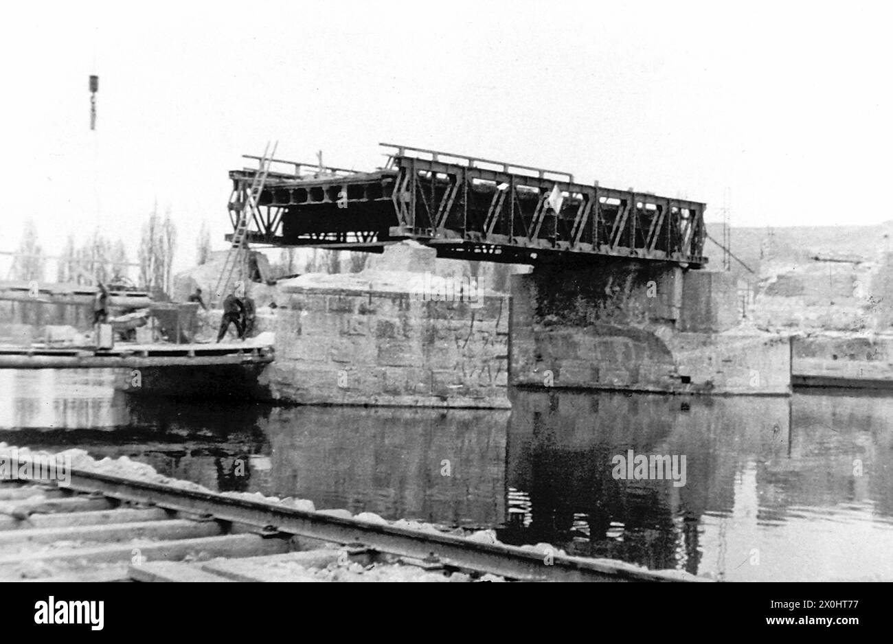 Am 1. April 1945 sprengten deutsche Einheiten Arch 6 in der Mitte der Brücke. In den folgenden Jahren überspannte eine provisorische Holzkonstruktion die Lücke im Gebäude. Der Eröffnung der Neuen Hauptbrücke 1954 folgte der Wiederaufbau der Alten Hauptbrücke, der 1957 abgeschlossen wurde. Durch den Ausbau des Mains zu einer wichtigen Schifffahrtsroute wurden die drei Mittelbögen fünf bis sieben durch einen rund 58 Meter langen Spannbetonbalken ersetzt, der den Main überspannte, der durch das Goßmannsdorfer Stauwerk gestaut wurde. [Automatisierte Übersetzung] Stockfoto