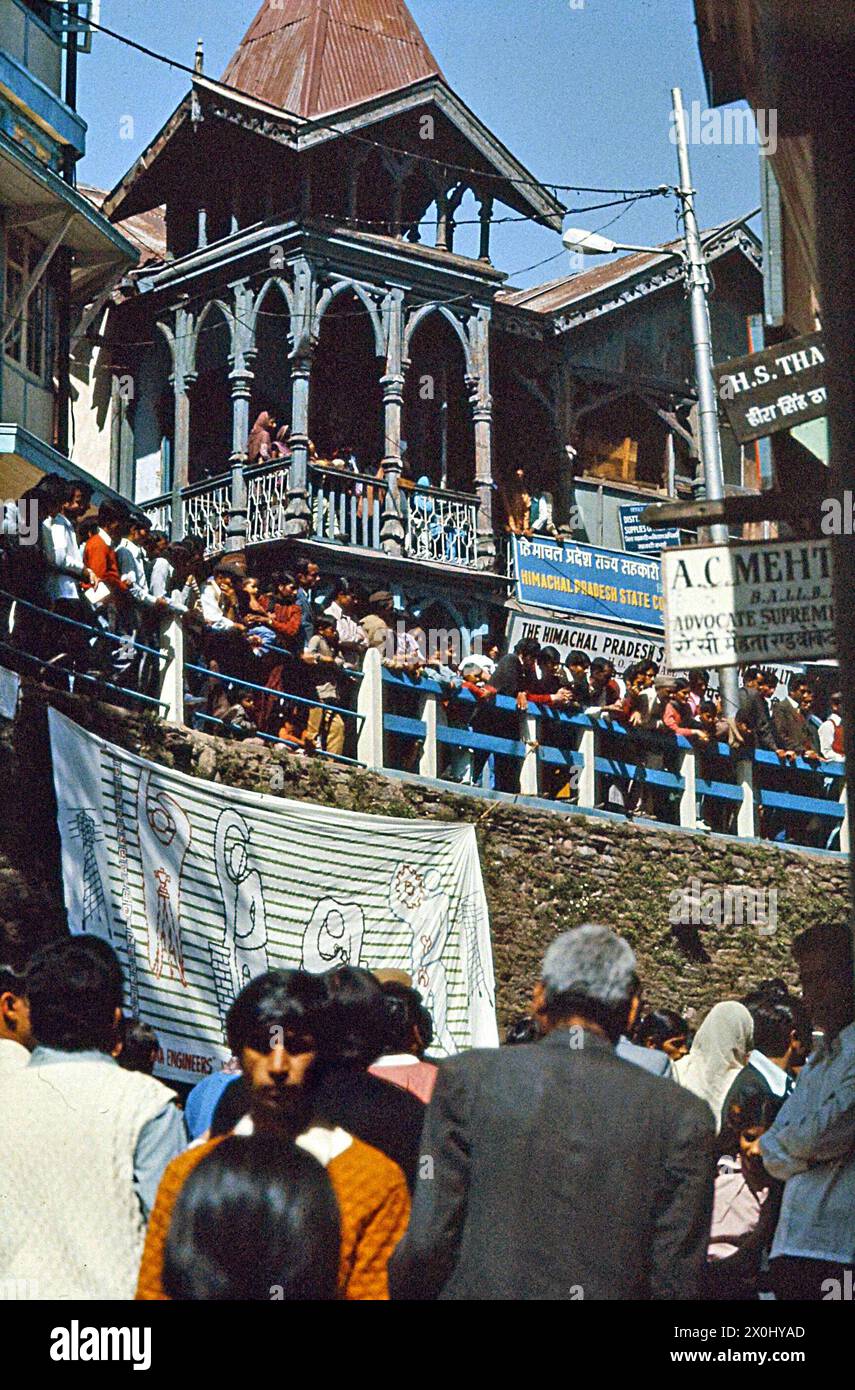 Besucher beim Besuch der ehemaligen indischen Premierministerin Indira Gandhi in Shimla. Die Menschen drängen sich auf einer Straße und an einer Wand darüber. Auch in den dahinter liegenden Häusern und auf den Balkonen sind Menschen zu sehen. An der Wand ist ein großes Banner angebracht. [Automatisierte Übersetzung] Stockfoto