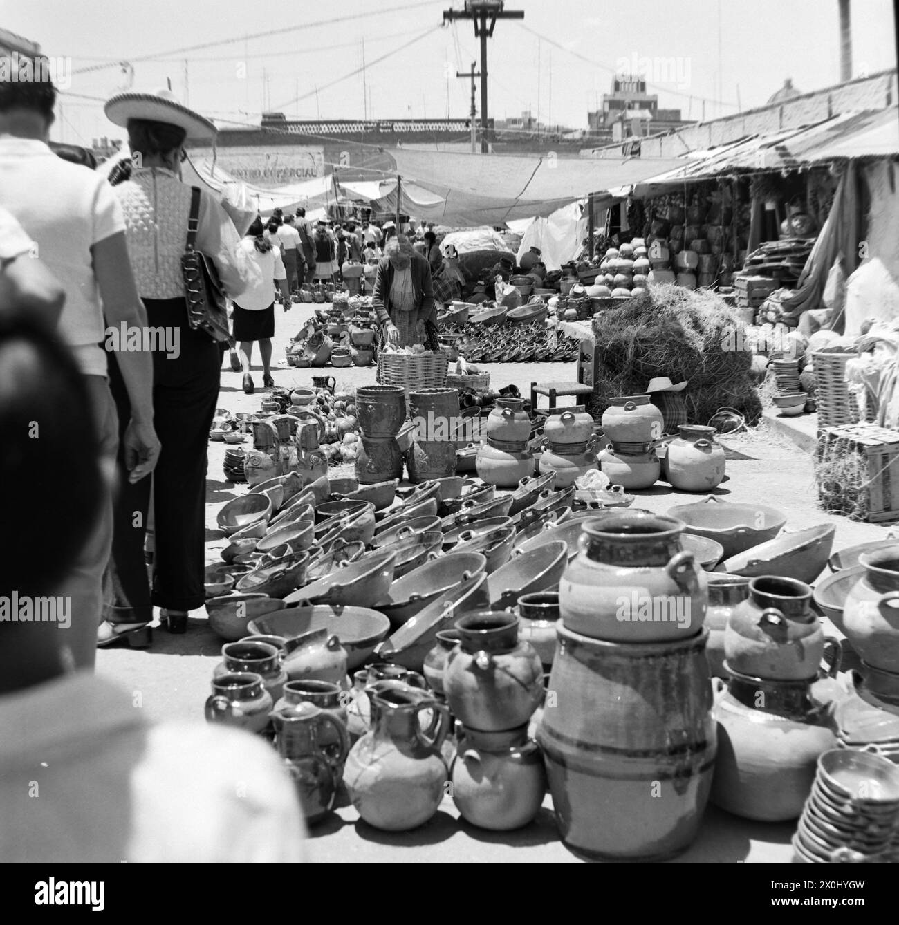 Blick auf den Markt in Toluca in Mexiko. Mehrere Händler haben ihre Keramik an Decken und Planen auf dem Boden verbreitet. Mehrere Leute schauen sich die angebotenen Waren an. Darunter sind Tonkrüge und Schüsseln. [Automatisierte Übersetzung] Stockfoto