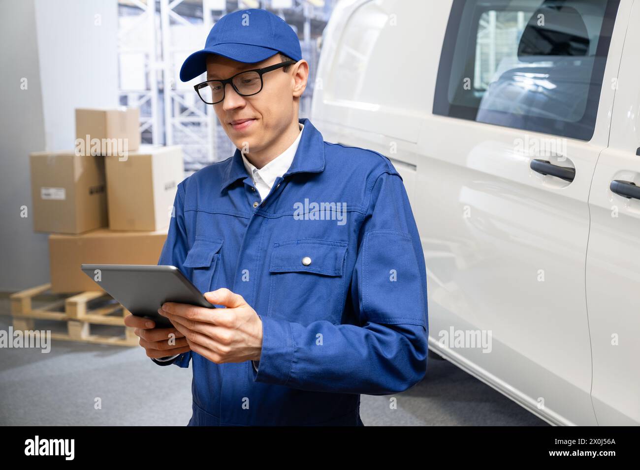 Manager mit einem digitalen Tablet im Hintergrund des Transporters. Flotten- und Lagerverwaltung. Stockfoto