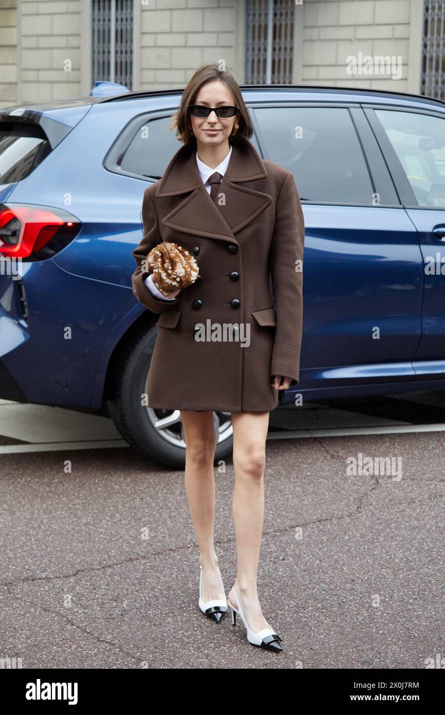 MAILAND, ITALIEN - 23. FEBRUAR 2024: Frau mit braunem Mantel und weißen und schwarzen Schuhen vor der Philosophie von Lorenzo Serafini, Milan Fashion W Stockfoto