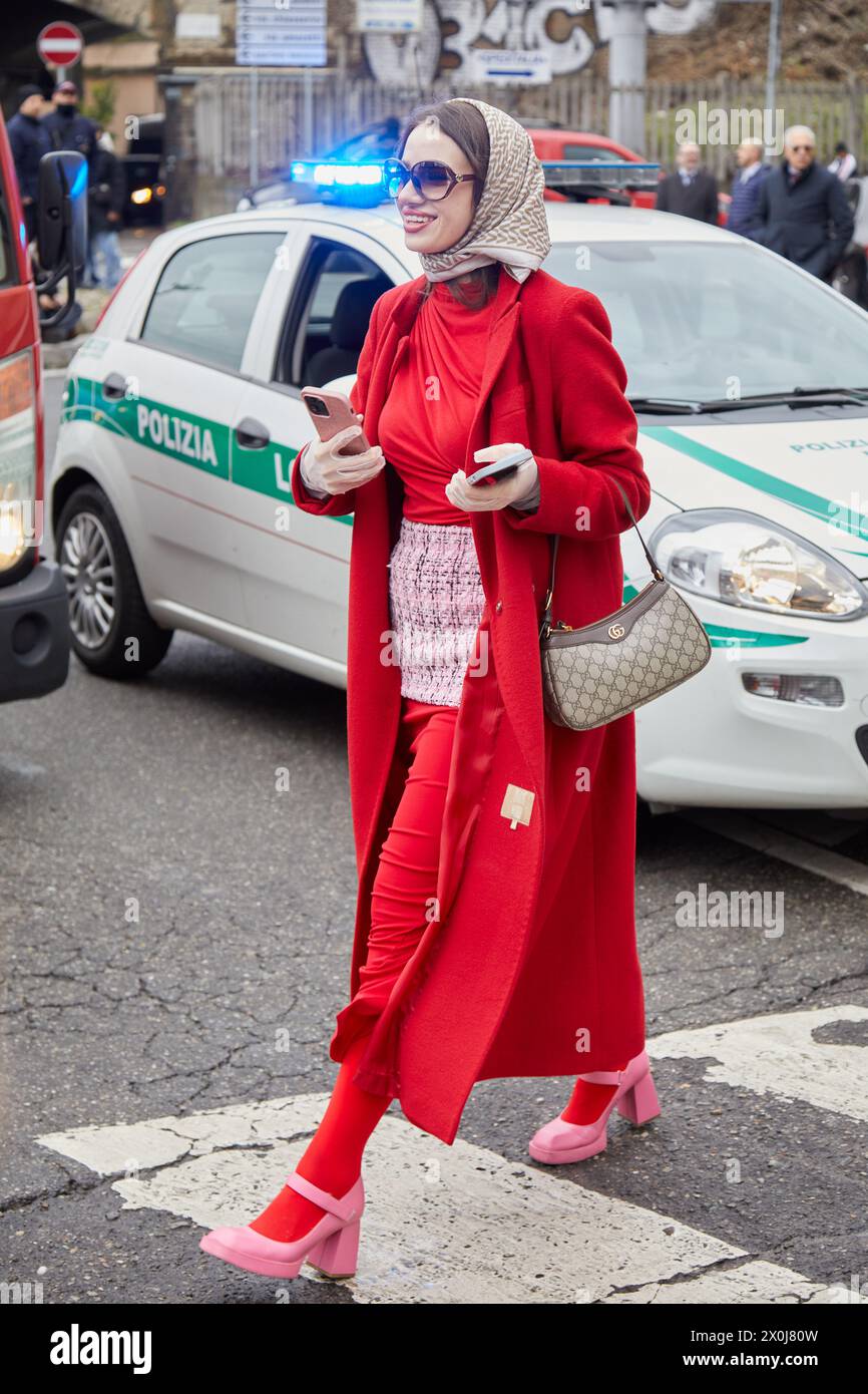 MAILAND, ITALIEN - 23. FEBRUAR 2024: Frau mit rotem Mantel und Gucci-Tasche vor der Gucci Fashion Show, Mailand Fashion Week Street Style Stockfoto
