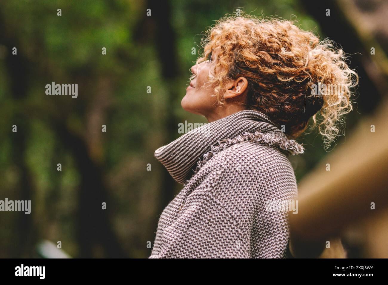 Seitenportrait einer Frau, die sich in der Natur entspannt. Innere Balance und Achtsamkeit Konzept Momente. Stehende weibliche Menschen im Wald genießen Stille und gute Natur vibes allein lächelnd und bewundernd Stockfoto