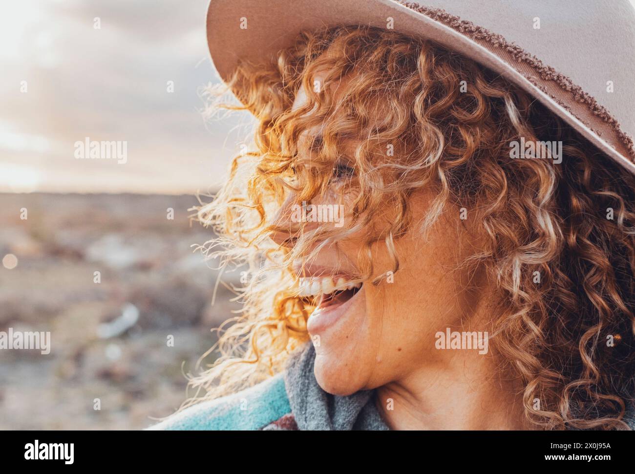 Seitenportrait von überglücklich und aufgeregt fröhlich hübsche Frau mit lockigen blonden Haaren und Hut viel Spaß in Outdoor-Reisen Freizeitaktivitäten. Weibliche Touristen lächeln und lachen viel auf dem Land Stockfoto