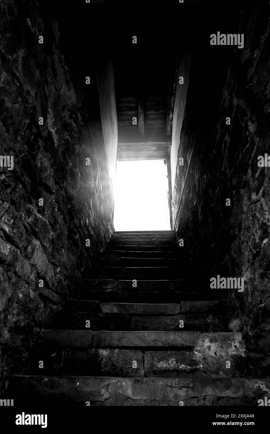 Dunkle alte Treppe mit hellem Ausgang Stockfoto