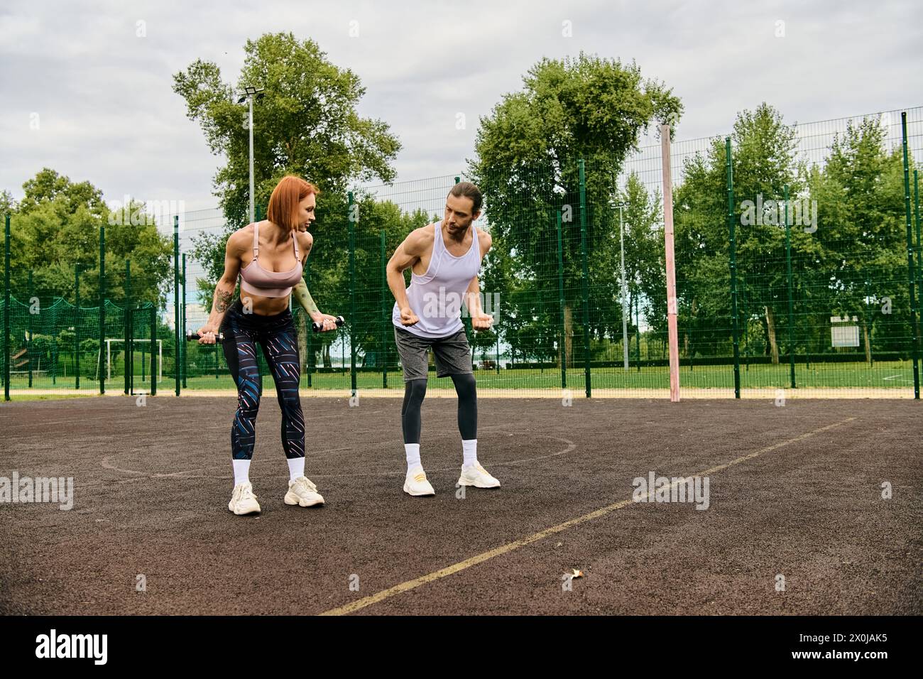Zwei sportliche Frauen in Sportbekleidung stehen selbstbewusst an der Spitze eines Tennisplatzes und zeigen Entschlossenheit und Motivation. Stockfoto