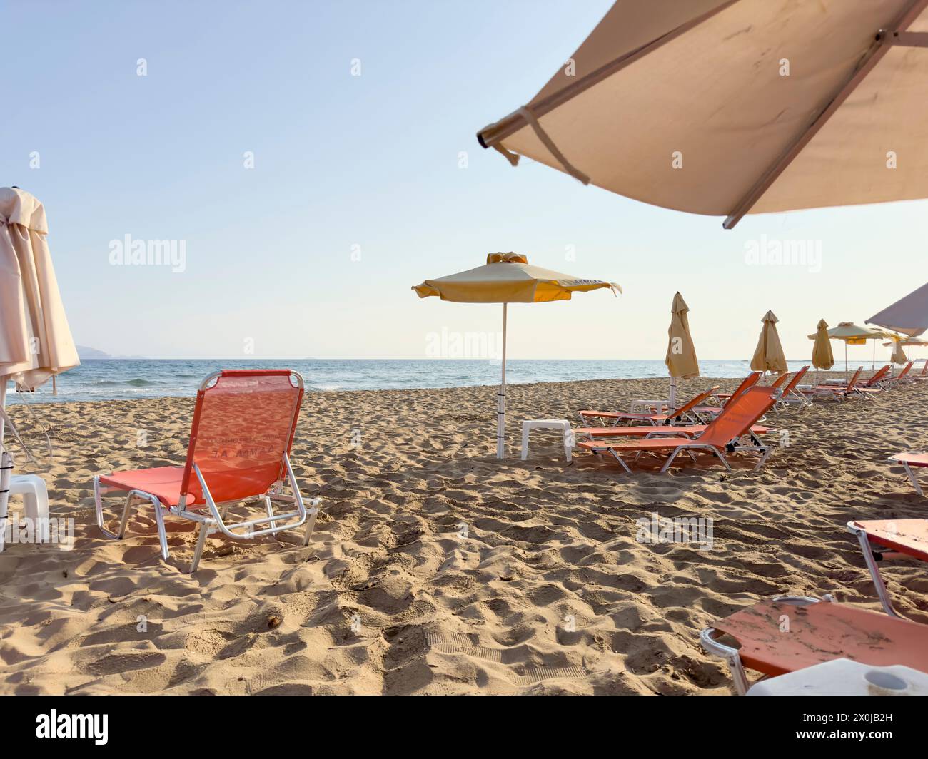 Leere Liegestühle am frühen Morgen am Strand von Gouves auf der Urlaubsinsel Kreta Stockfoto