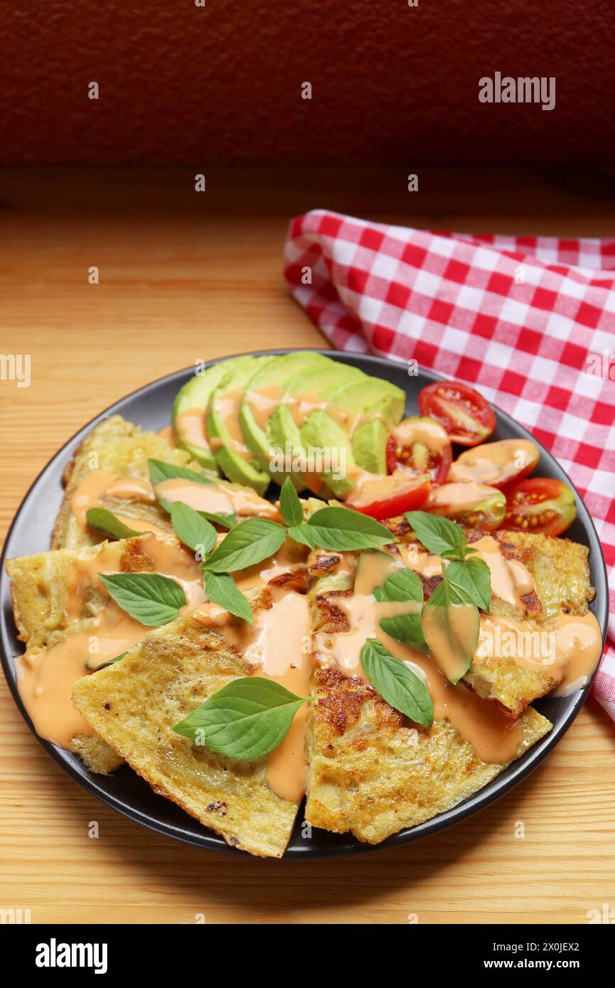 Teller mit hausgemachtem spanischem Omelett oder Tortilla Espanola mit Avocado und Tomatensalat Stockfoto