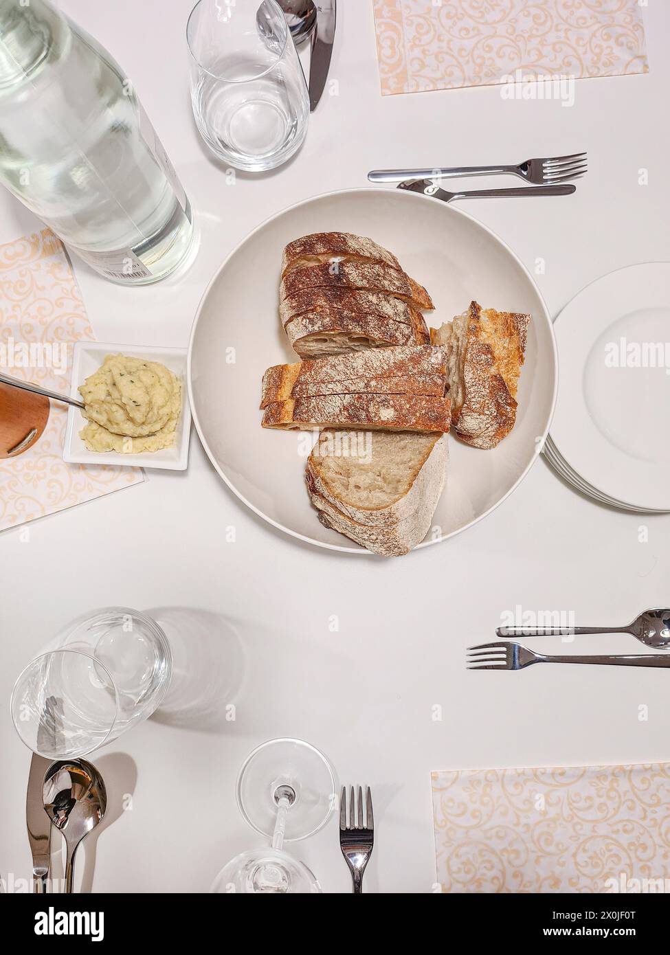 In Scheiben geschnittenes Brot in einer weißen Schüssel auf einem gedeckten Tisch Stockfoto