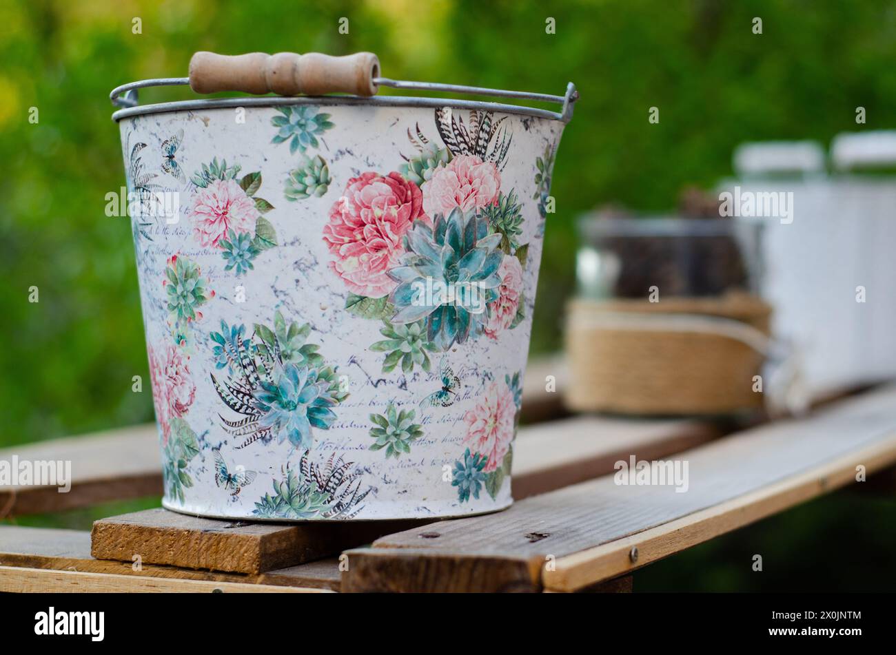 Garteneimer mit Blumenmuster auf Holzbrettern Stockfoto