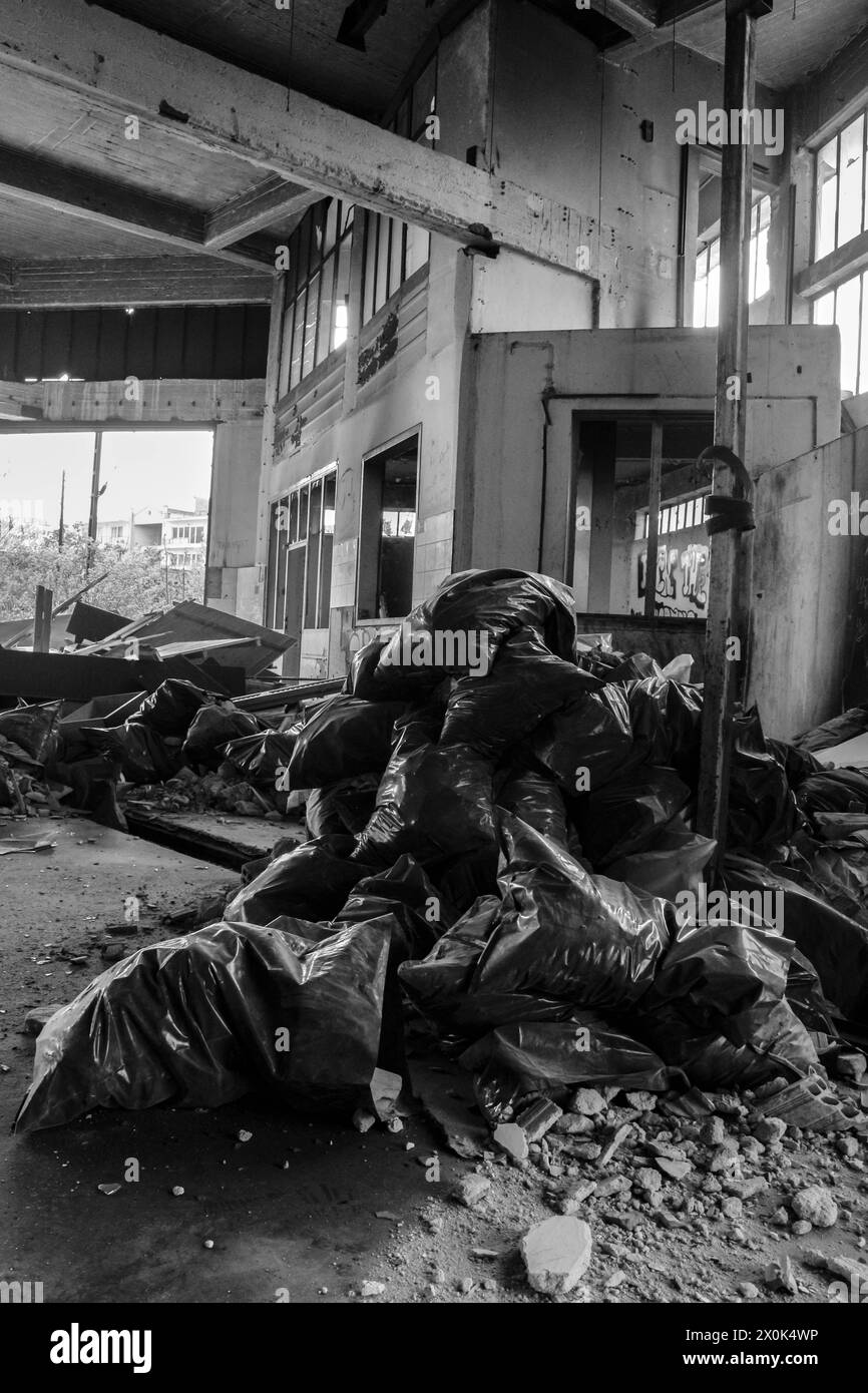 Werfen Sie einen Blick in die düstere Unterwelt des urbanen Lebens mit diesem fesselnden Bild, das in den verlassenen Straßen der Stadt zahlreiche Müllsäcke einfängt. Stockfoto