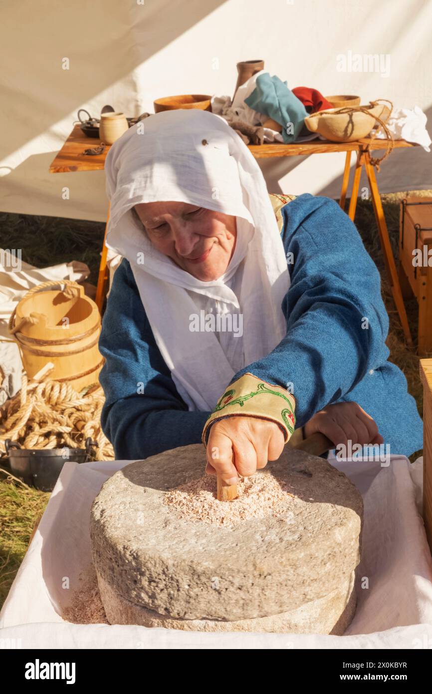 England, East Sussex, Battle, das jährliche Oktober Battle of Hastings Re-enactment Festival, Woman Hand Grinding, um Mehl herzustellen Stockfoto