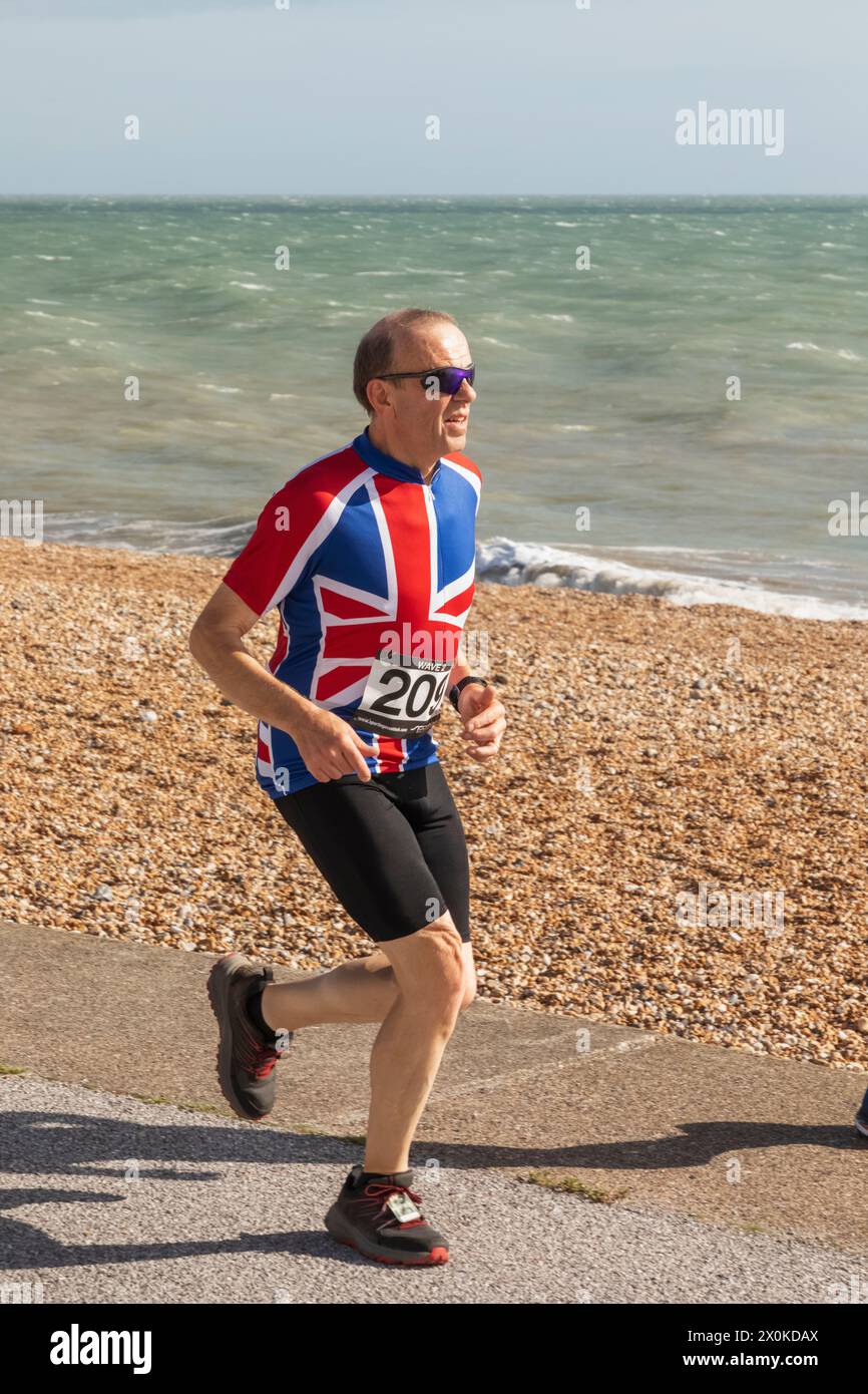 England, Kent, Deal, Deal Beach, Jogger mit Union Jack T-Shirt Stockfoto