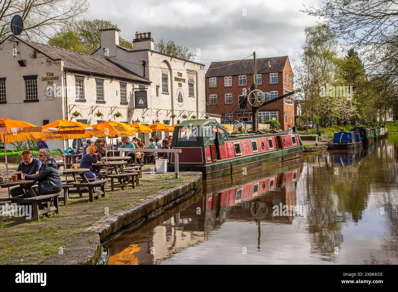 Schmalboote auf dem Shropshire union Kanal vor dem Shroppie fly Pub im Dorf Cheshire Audlem, wo Menschen essen und trinken Stockfoto