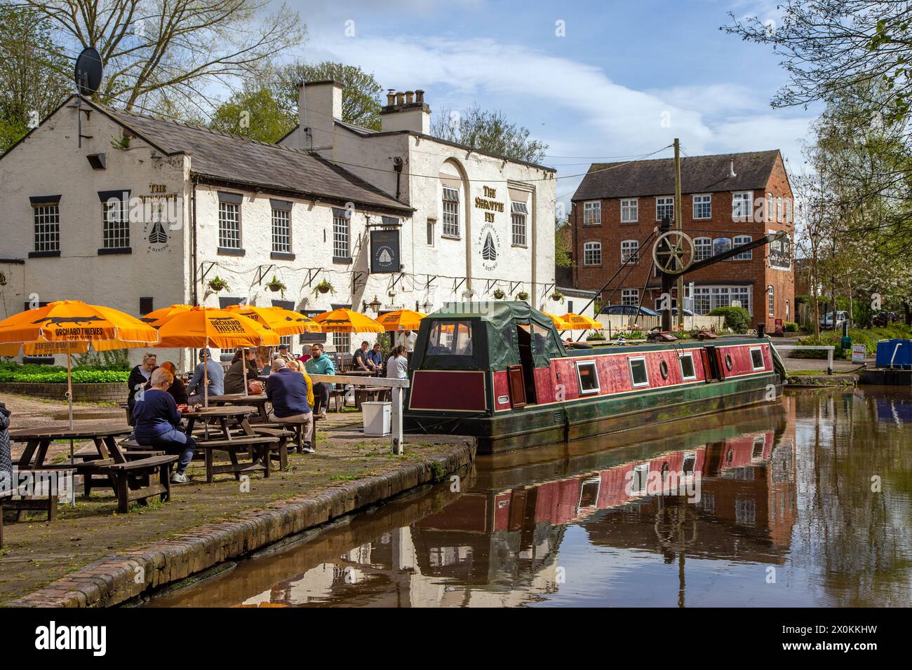 Schmalboote auf dem Shropshire union Kanal vor dem Shroppie fly Pub im Dorf Cheshire Audlem, wo Menschen essen und trinken Stockfoto