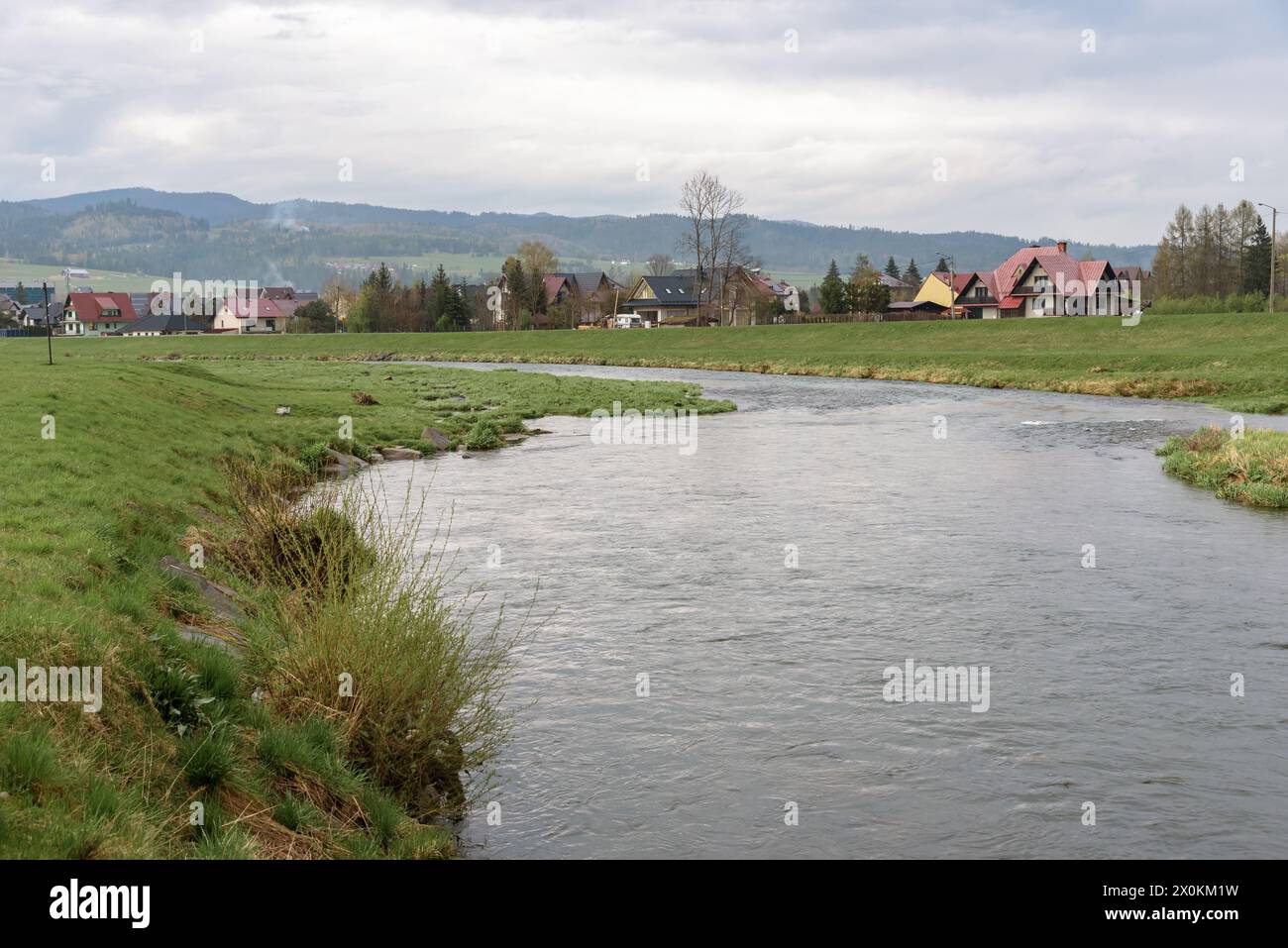 Blick auf den Fluss Bialy Dunajec mit Wohnhäusern im Hinterland in der Stadt Nowy Targ, Polen Stockfoto