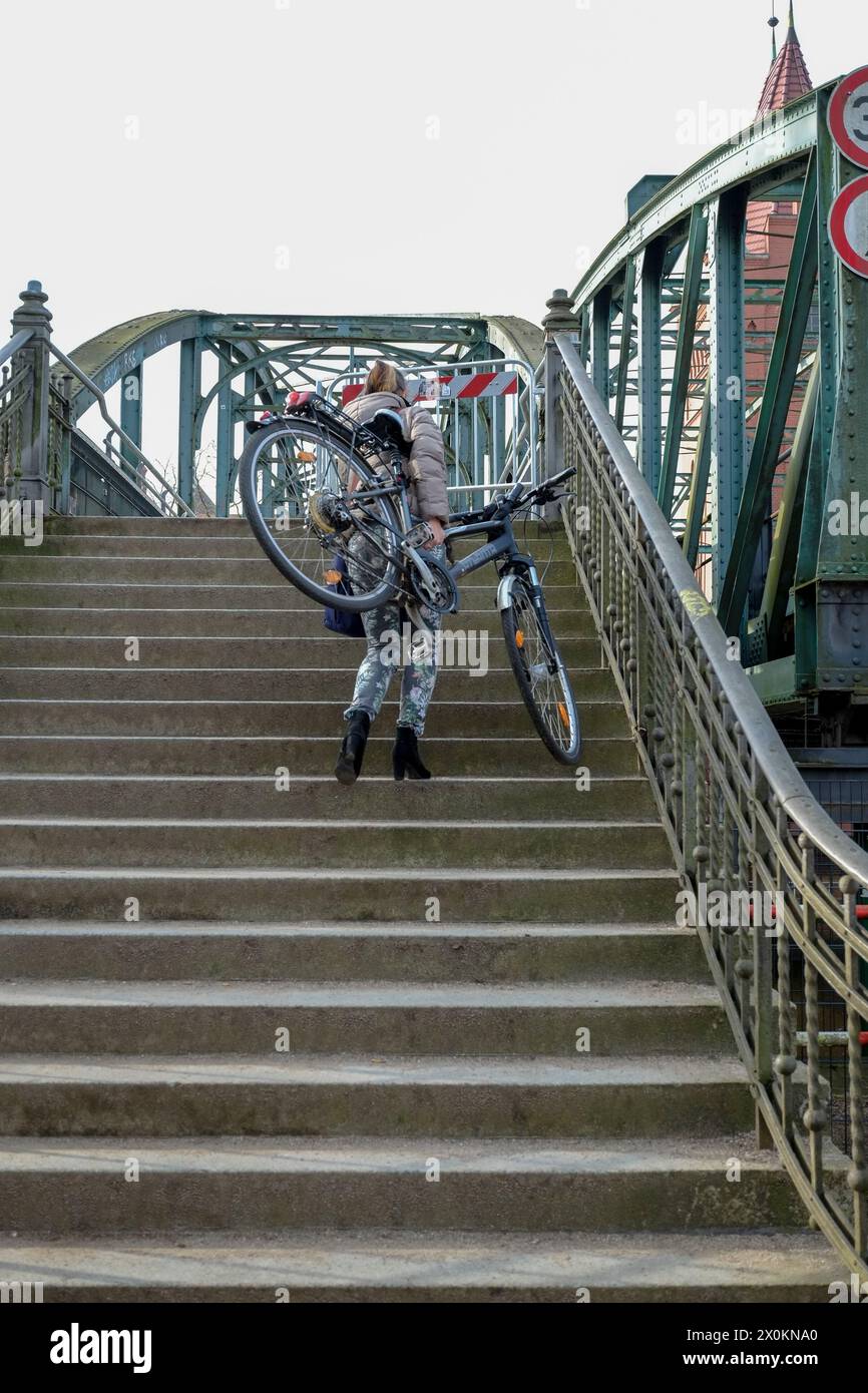 Frau trägt Fahrrad eine Treppe hinauf, keine Zugänglichkeit Stockfoto