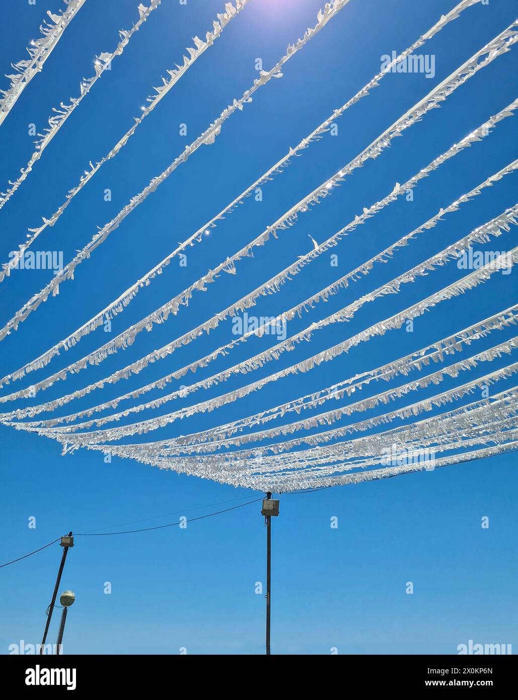 Eine weiße Girlande hängt festlich dekoriert über einem öffentlichen Platz in Cala Ratjada, festliche Dekoration für eine Party, Sommerurlaub auf Mallorca, Spanien Stockfoto