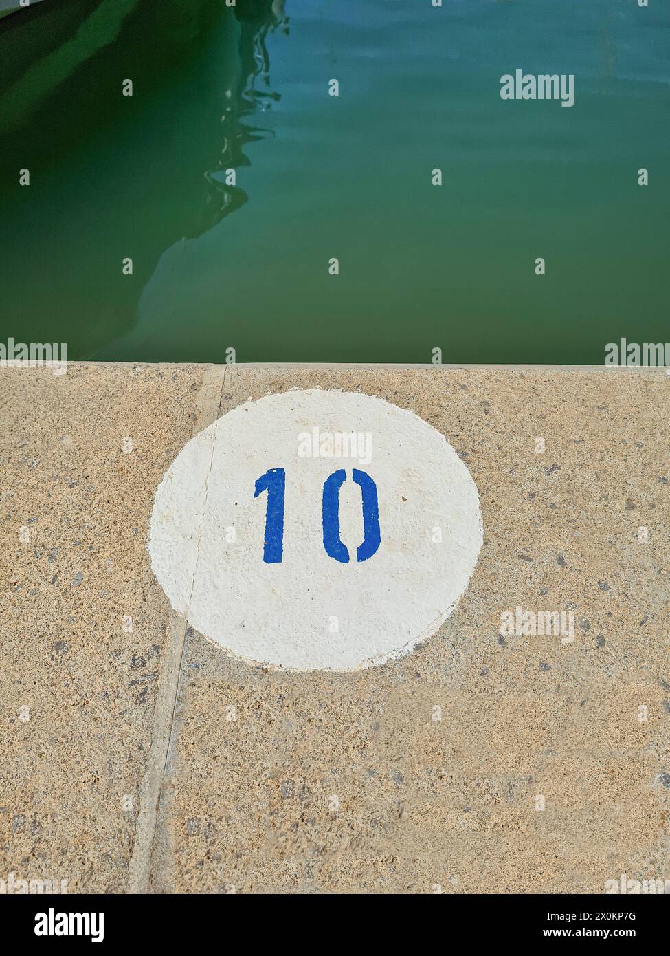 Ein weißer runder Kreis mit der blauen Zahl 10, Markierung auf Steinboden, Hafen, Mallorca, Spanien Stockfoto