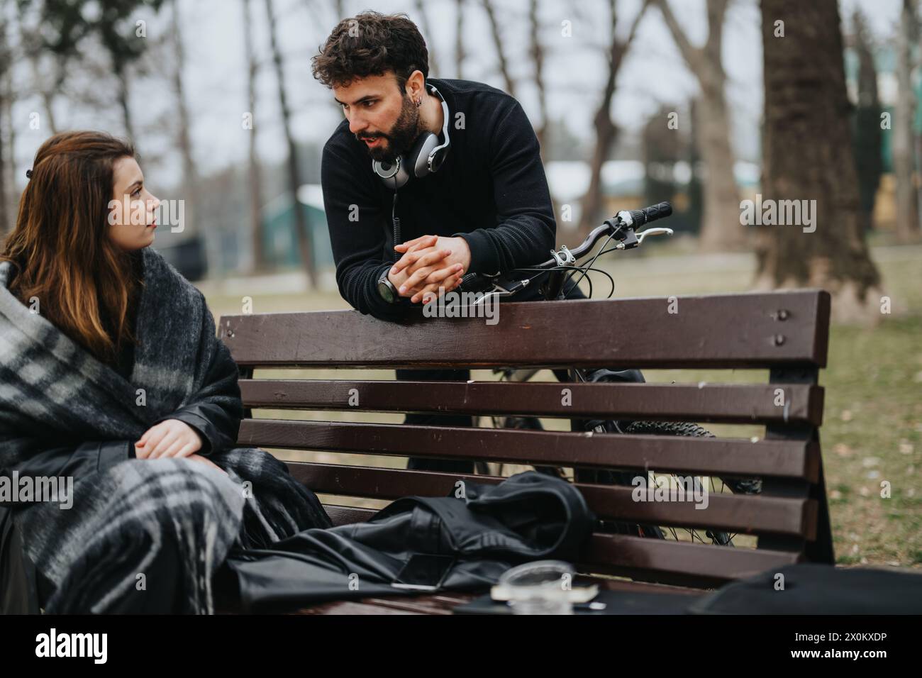 Zwangloses Gespräch zwischen Mann und Frau, die mit dem Fahrrad auf der Parkbank sitzen. Stockfoto