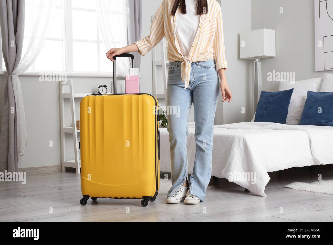 Frau mit Koffer, Reisepass und Tickets in einem hellen Hotelzimmer Stockfoto