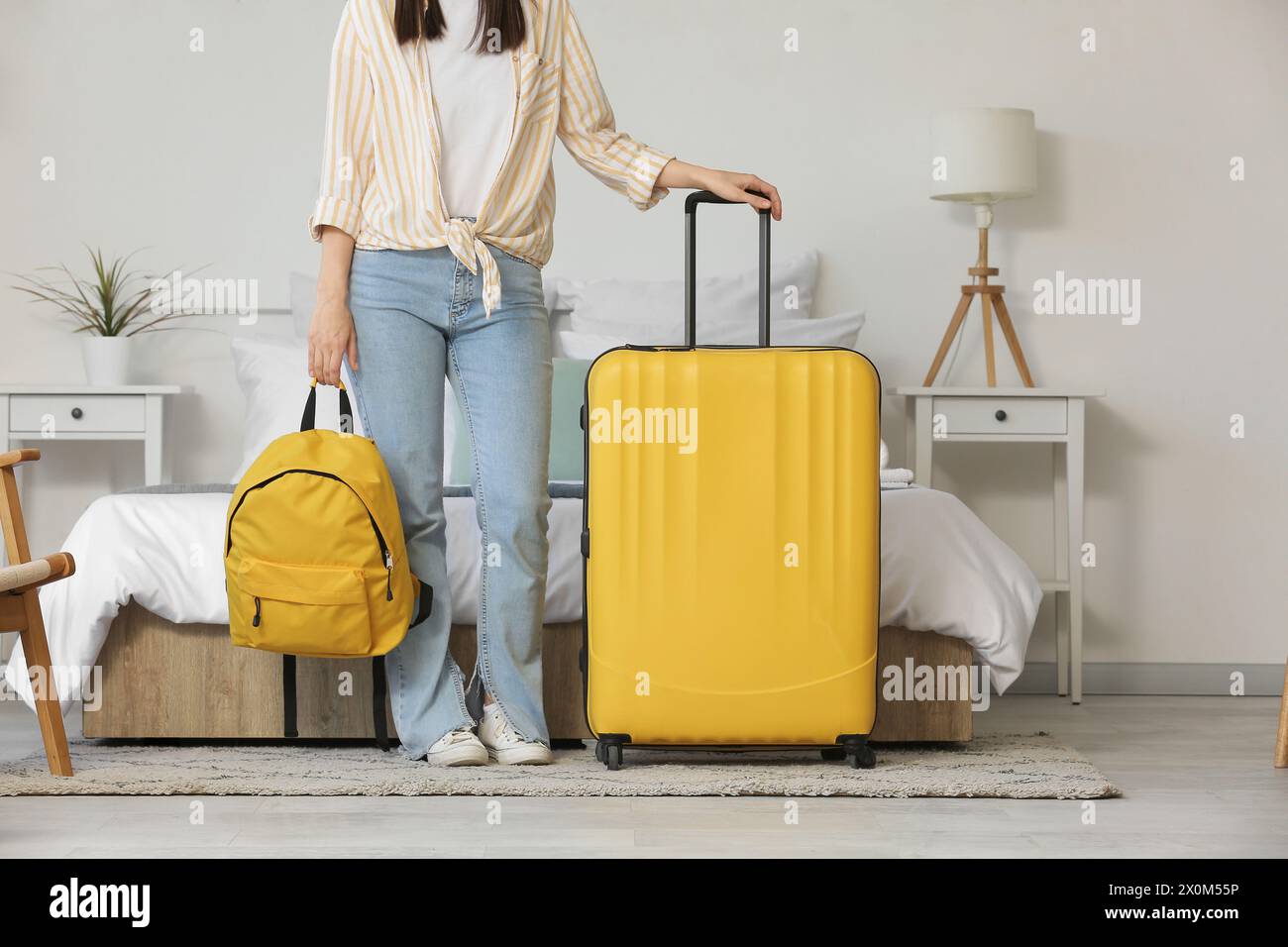 Frau mit Koffer und Rucksack in hellem Hotelzimmer Stockfoto
