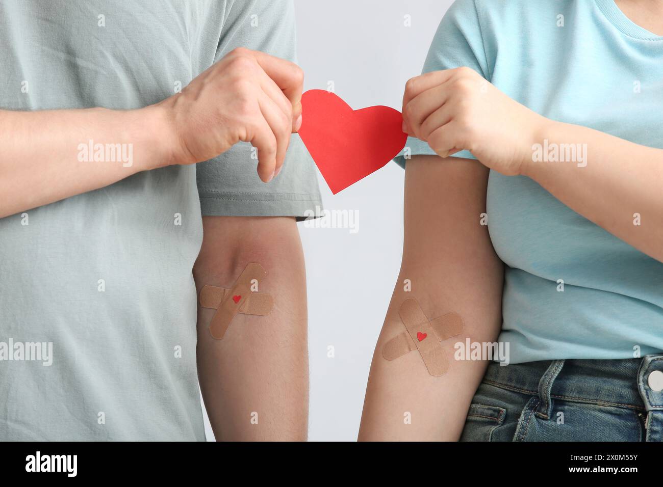 Blutspender mit applizierten medizinischen Pflastern und Papierherz auf grauem Hintergrund, Großaufnahme Stockfoto
