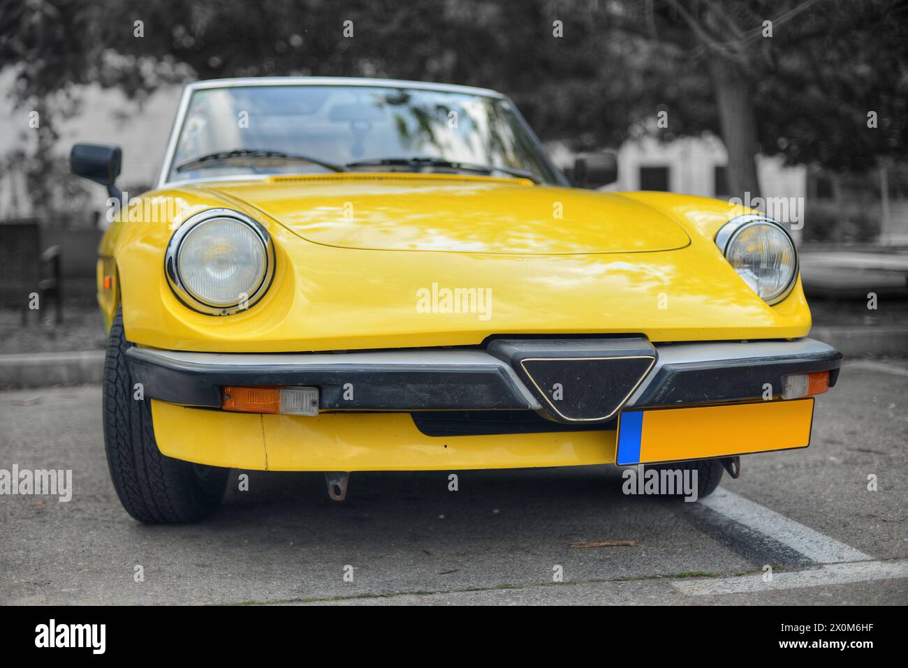 Ein frontales Foto eines gelben italienischen Roadsters in selektiver Farbe Stockfoto