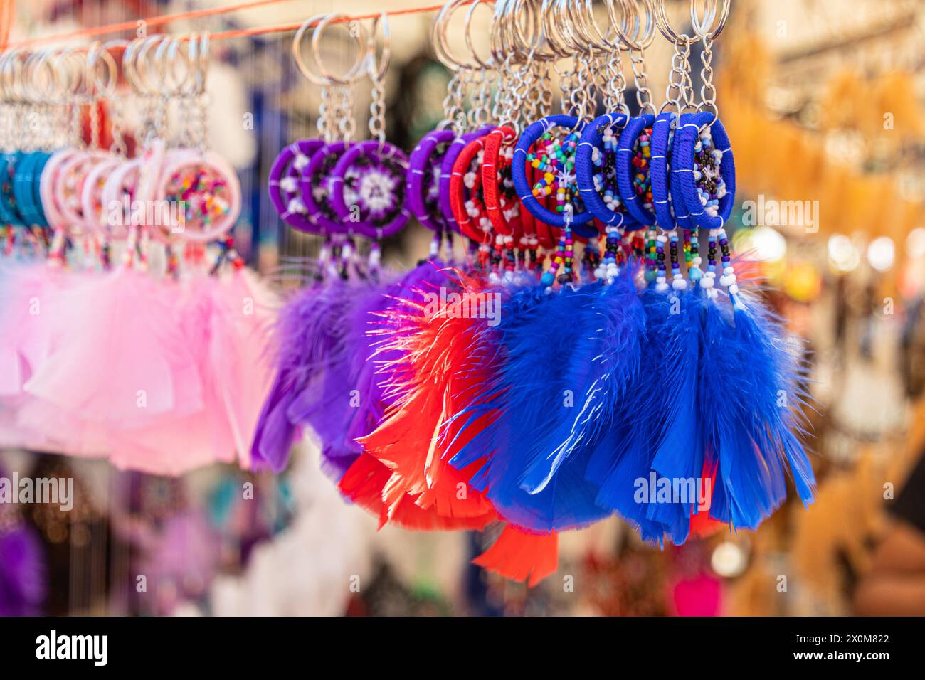 Bunte blaue, rote, rosa und lila Traumfänger mit Vogelfedern auf einem Kunsthandwerksmarkt in Ecuador. Selektiver Fokus Stockfoto