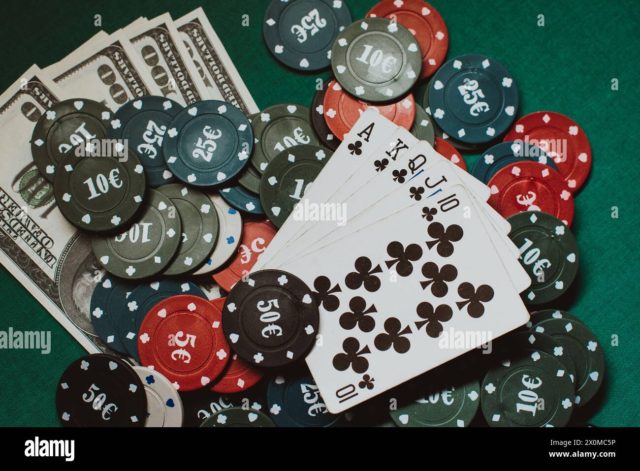 Karten mit einem Royal Flush auf einem Haufen Chips und Geld Dollars in einem Spiel mit Poker Stockfoto