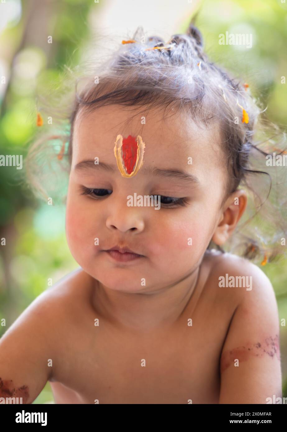 Niedlicher indischer Junge mit heiligem religiösem Symbol auf dem Kopf im Freien mit verschwommenem Hintergrund Stockfoto