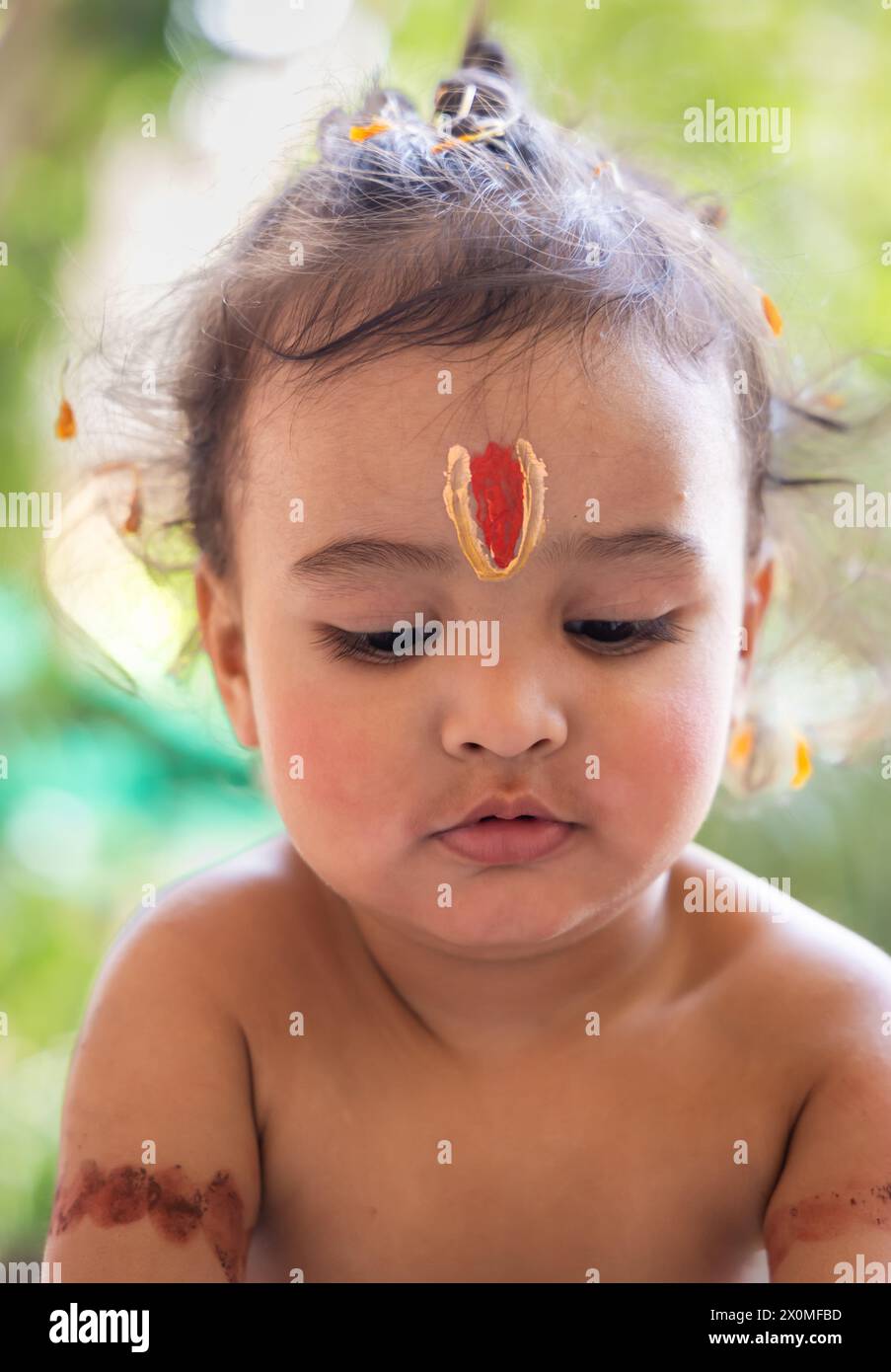 Niedlicher indischer Junge mit heiligem religiösem Symbol auf dem Kopf im Freien mit verschwommenem Hintergrund Stockfoto