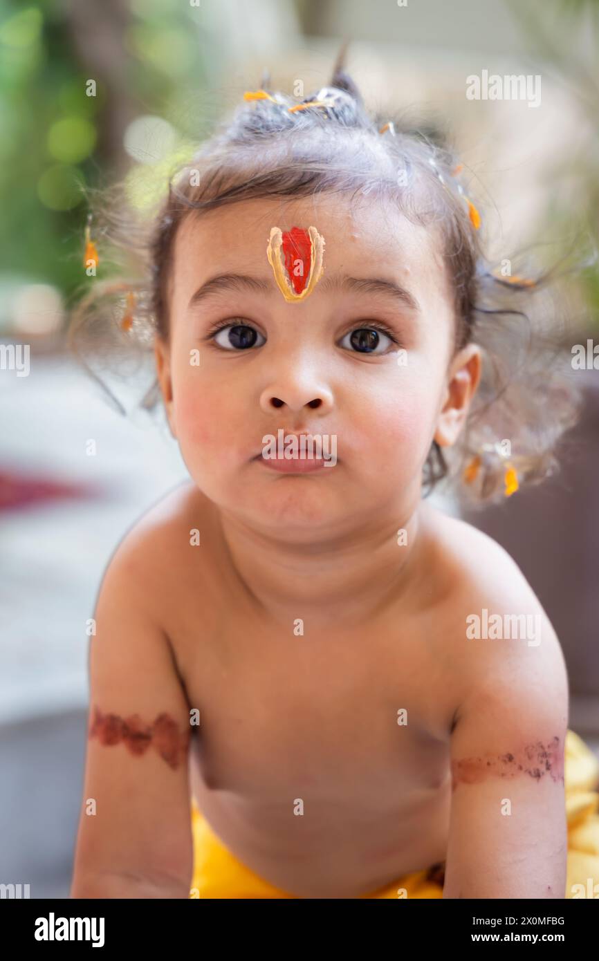 Niedlicher indischer Junge mit heiligem religiösem Symbol auf dem Kopf im Freien mit verschwommenem Hintergrund Stockfoto