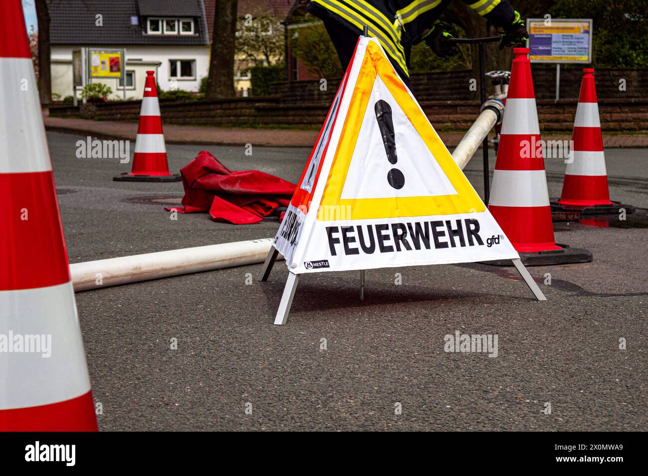 Osnabrück, Deutschland 06. April 2024: Im Bild: Bei einem Brand hat die Feuerwehr eine Absperrung um eine Löschleitung, Löschschlauch mit Leitkegel, Pylonen errichtet. Zusätzlich steht ein Faltsignal mit der Aufschrift Feuerwehr auf der Fahrbahn. Niedersachsen *** Osnabrück, Deutschland 06 April 2024 im Bild im Brandfall hat die Feuerwehr eine Absperrung um eine Löschlinie errichtet, Löschschlauch mit Kegel, Pylonen es gibt auch ein Falzsignal mit der Aufschrift Feuerwehr an der Straße Niedersachsen Copyright: XFotostandx/xReissx Stockfoto