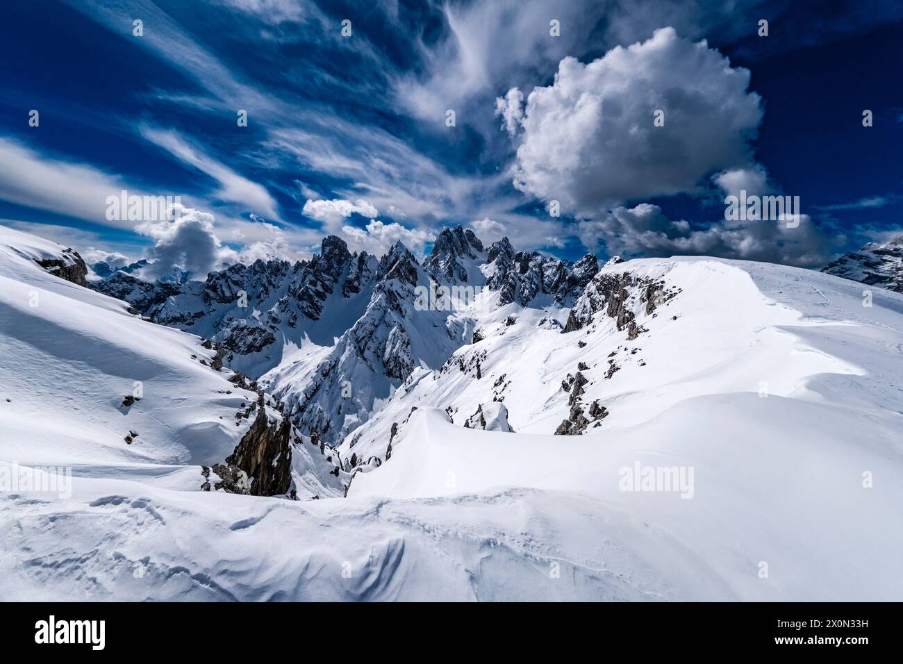 Schneeschwankungen schaffen kunstvolle Strukturen im Naturpark Tre Cime im Winter, die Gipfel von Cadini di Misurina in der Ferne, vom Monte Campedele aus gesehen. Stockfoto